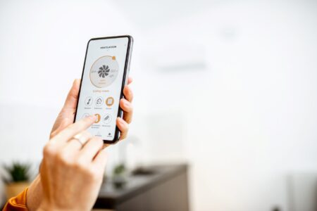 Image showing a person using a smartphone to control home automation system devices.