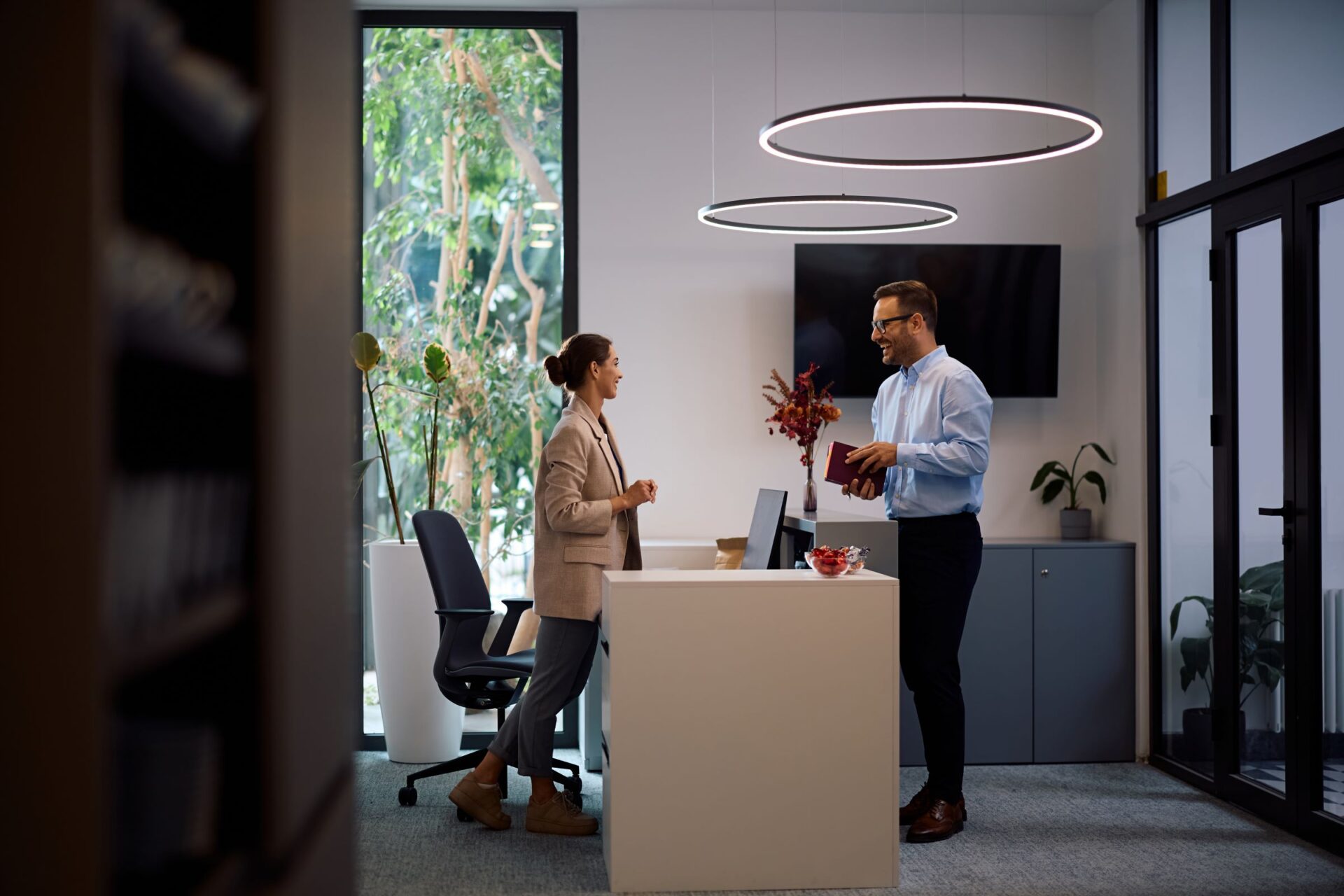 Happy business colleagues talking while working in the office under commercial lighting that was done by Kish & Sons Commercial Electrical Services.