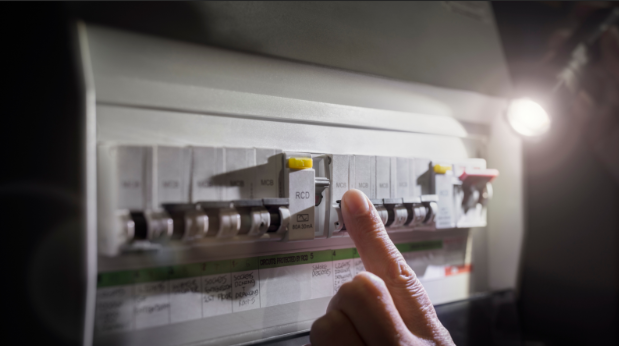 A person inspecting their circuit breaker box with a flashlight